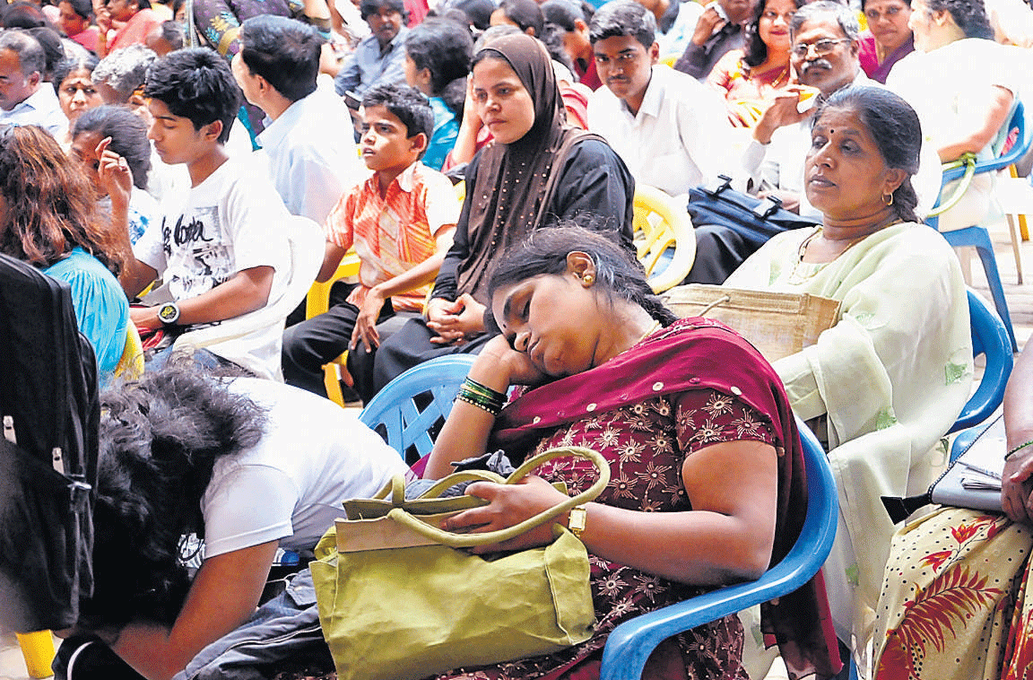 A tedious wait: An exhausted parent takes a quick nap at the CET counselling in Bangalore on Wednesday. DH Photo
