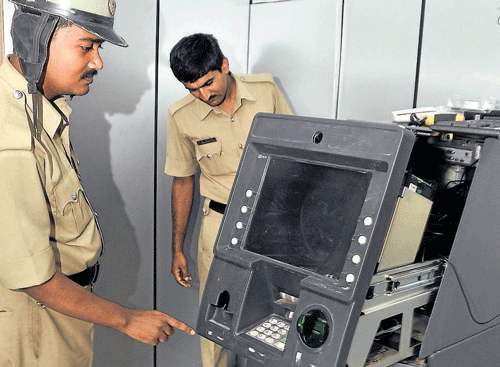 Policemen inspect the Canara Bank ATM kiosk at Nagashetty Halli on Sunday. dh Photo