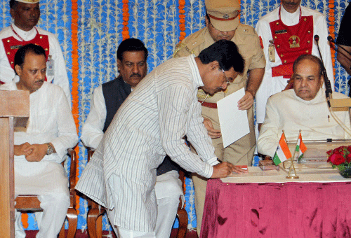 Maharashtra Governor K Shankarnarayan, CM Prithviraj Chavan and Deputy CM Ajit Pawar look on as NCP leader Dilip Sopal signing a paper during the swearing in ceremony at Raj Bhavan in Mumbai on Tuesday. PTI Photo