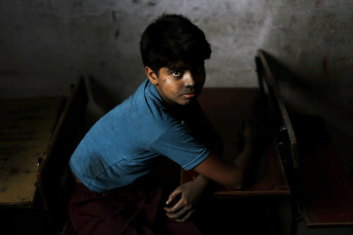 A young bonded child laborer rests at a school desk in a safe house after being rescued during a raid by workers from Bachpan Bachao Andolan or Save the Childhood Movement, at a factory in New Delhi, India, Tuesday, June 11, 2013. More than 58 child laborers were rescued by the NGO in the Indian capital Tuesday, the agency said. AP photo