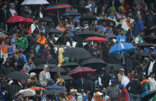 India fans hold umbrellas as rain delays play during the ICC Champions Trophy group B cricket match between India and West Indies at The Oval cricket ground in London, Tuesday, June 11, 2013. AP photo