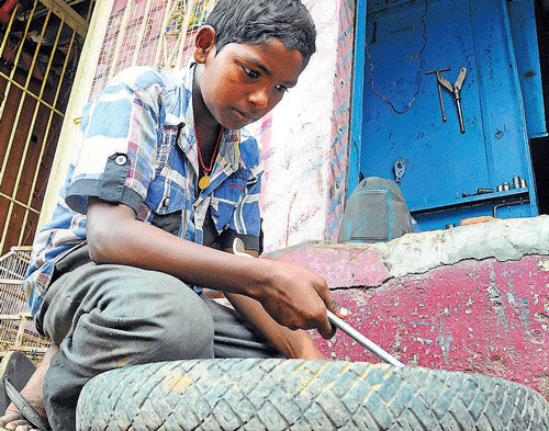 Tender hands Even as the world observes 'World Day Against Child Labour Day,' a boy toils away in a garage at Indira Nagar. DH photo