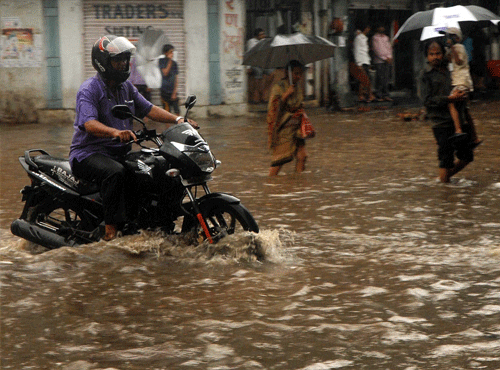 People wade through flooded street after heavy downpour in Mumbai on Friday. PTI Photo