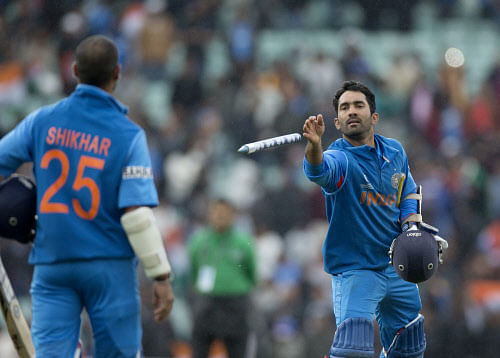 Dinesh Karthik, right, throws a stump to his teammate Shikhar Dhawan to keep after he scored 102 to help give their side victory runs as they walk off at the end of the ICC Champions Trophy group B cricket match between India and West Indies at The Oval cricket ground in London, Tuesday, June 11, 2013. AP photo