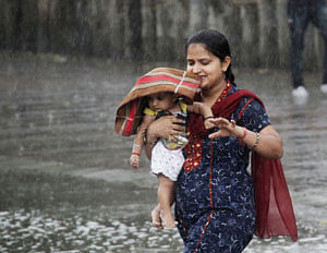 A woman carries her child through a heavy rain shower in the northern Indian city of Chandigarh June 11, 2013. India's monsoon rains recorded higher than average levels in the first week of the four-month rainy season, weather office sources told Reuters on June 6, reflecting a timely onset and progress so far over southern states. REUTERS