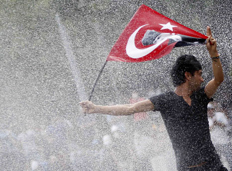 A protester is attacked by water cannon during crowds in Kizilay square in central Ankara, June 16, 2013. The unrest, in which police fired teargas and water cannon at stone-throwing protesters night after night in cities including Istanbul and Ankara, left four people dead and about 5,000 injured, according to the Turkish Medical Association. REUTERS.