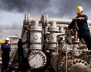 FILE - In this Dec. 13, 2009 file photo, Iraqi laborers work at the Rumaila oil refinery, near the city of Basra.  AP Photo