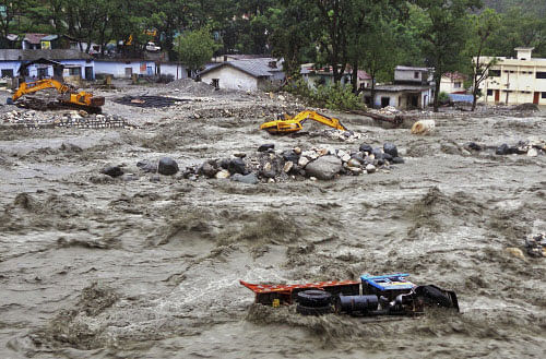 Bulldozer and other vehicles are drifted in a flooded river in Uttarkashi district, India, Monday, June 17, 2013. Torrential rain and floods washed away buildings and roads, killing at least 23 people on Monday in the northern Indian state of Uttarakhand, officials said Monday. AP Photo.