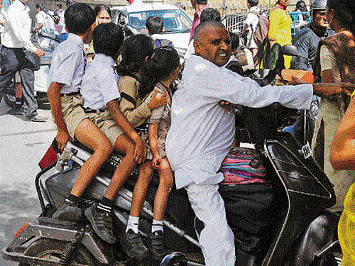 balancing act: As private vehicles carrying schoolchildren stayed off the roads, parents had to struggle to take their wards to school and back, in Bangalore on Wednesday. DHPhoto/ S k dinesh