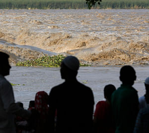 People watch the rising waters of river Yamuna in New Delhi June 20, 2013. India's monsoon rains could ease soon after hitting 89 percent over averages in the week to June 19, according to weather office sources, in a third straight week of downpours that have caused major flooding in north India. REUTERS