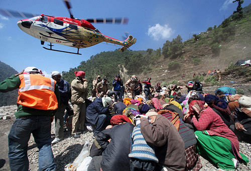 IAF helicopter Sarang landing for rescue operations as stranded pilgrims get down at Gauri Kund in Uttarakhand on Friday. PTI Photo.