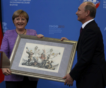 Russia's President Vladimir Putin (R) presents a historical lithograph to Germany's Chancellor Angela Merkel during a news conference after their meeting at the St. Petersburg International Economic Forum in St. Petersburg, June 21, 2013. REUTERS