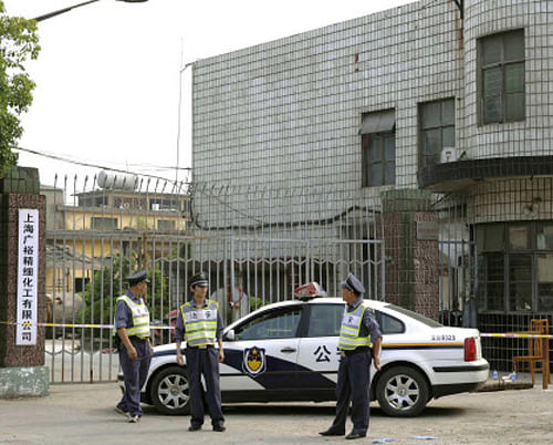 In this photo released by China's Xinhua News Agency, security officers stand guard at the murder site of a chemical factory in Baoshan District, east China's Shanghai Municipality, on Sunday, June 23, 2013. In a rare case of gun violence in China, a man fatally shot five people and beat a sixth to death, including some of his factory colleagues and a soldier, police said Sunday. AP Photo.