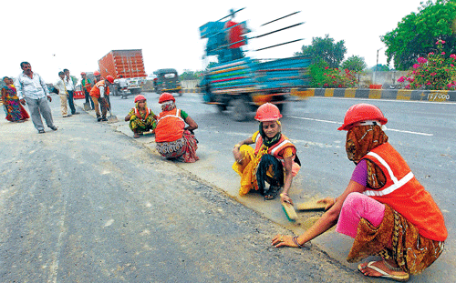 A file photo of workers cleaning the road before building a highway on the outskirts of Ahmedabad recently. Reuters
