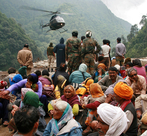 Stranded people wait for their turn to be rescued by a helicopter after heavy rains in the Himalayan state of Uttarakhand June 23, 2013. Flash floods and landslides unleashed by early monsoon rains have killed at least 560 people in Uttarakhand and left tens of thousands missing, officials said on Saturday, with the death toll expected to rise significantly. REUTERS