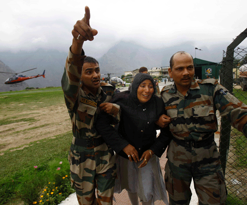 An injured Indian pilgrim cries as Indian army soldiers carry her after she was rescued from the higher reaches of mountains, at a makeshift helipad at Joshimath, in northern Indian state of Uttarakhand, Monday, June 24, 2013. A top official said the death toll in northern India could rise as army soldiers clear the debris from towns and villages flattened by landslides and monsoon flooding. Home Minister Sushilkumar Shinde said the number of people who have perished in the floods that washed away thousands of homes could go beyond the 1,000 deaths reported so far. (AP Photo/