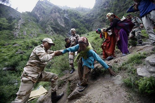 Army soldiers help stranded people climb down a mountain in Govindghat, India, Sunday, June 23, 2013. Bad weather hampered efforts Sunday to evacuate thousands of people stranded in the northern India state of Uttarakhand, where at least 1,000 people have died in monsoon flooding and landslides, army officials said. AP photo