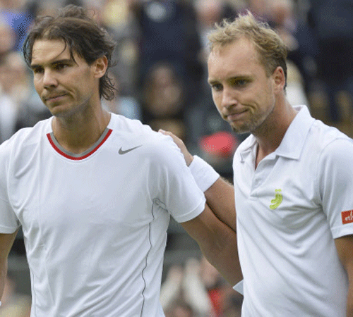 Rafael Nadal of Spain (L) and Steve Darcis of Belgium walk off the court after Nadal was defeated by Darcis in their men's singles first round tennis match at the Wimbledon Tennis Championships, in London June 24, 2013. REUTERS