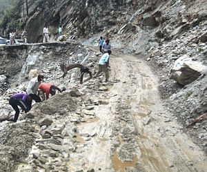 People clear road after landslide, in Gauchar on Monday.PTI Photo