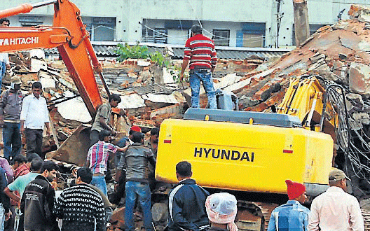 A huge cement tank collapsed on the excavator killing the operator on the spot near old bus stand in Hassan, on Tuesday. DH&#8200;PHOTO