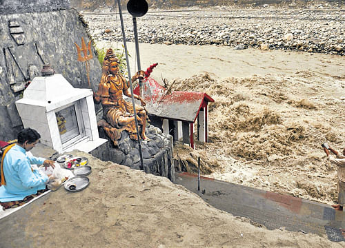 A devotee worhips at the bank of flooded the Bhagirathi river in Uttarkashi on Monday. PTI