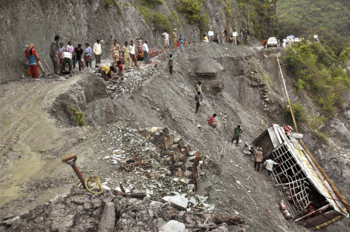 File image: People gather near a truck carrying LPG cylinders that fell in the Bhagirathi River from a road damaged after monsoon flooding in Uttarkashi, India.  AP Photo
