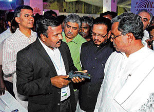 demonstration: A UIDAI officer explains Aadhar card activities to Chief Minister  Siddaramaiah in the City on Thursday. Minister Krishna Byregowda, MP D B Chandregowda and UIDAI chairman Nandan Nilekani are with him. DH Photo