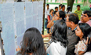 Students and parents search for their names in the first list of admissions brought out by a Delhi University college on Thursday. gautam chaman/ dh photo