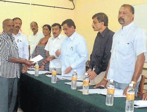 MLA K G Bopaiah distributes cheque to the family of a kin who was killed in an elephant attack, at the tri-monthly review meeting of Virajpet taluk panchayat at Ponnampet College of Forestry in Gonikoppa on Saturday. dh photo