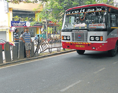 Pedestrians wait for the bus to pass to cross the road. dh photo