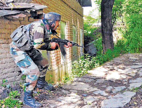 An army solider takes position near the house where militants were holed up during an encounter, at Tral in Pulwama on  Monday.  PTI