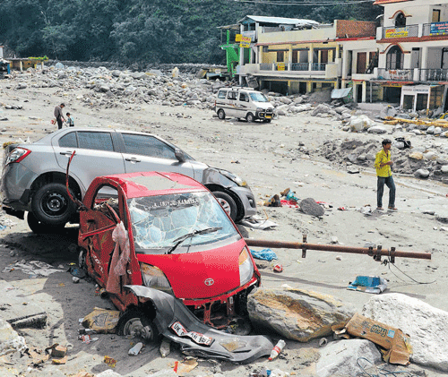Residents walk beside the wreckage of vehicles in Sonprayag in Uttarakhand on Tuesday. AFP