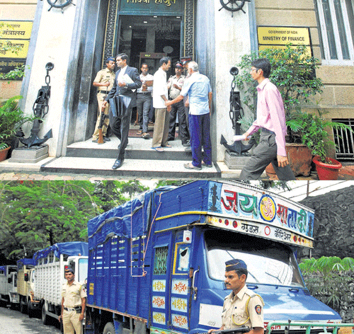 Policemen guard the trucks which were seized with around 150 bags of cash and jewellery worth Rs 200 crore, in Mumbai on Tuesday. PTI