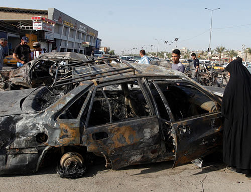 A woman inspects a burnt car at the site of a car bomb attack in Hurriya neighborhood in Baghdad July 3, 2013. At least 45 people were killed in bomb attacks across Iraq on Tuesday, most of them in busy markets and commercial areas of the capital Baghdad, police and medics said. REUTERS