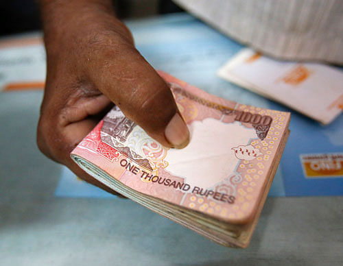 A customer hands a bundle of Indian Rupee currency notes to a teller at a financial institution in Mumbai . Reuters