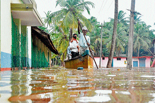 RaininG miseries: Residents take the help of a boat to reach their home in Ullal as the flash floods have inundated roads in the region on Thursday. DH&#8200;Photo