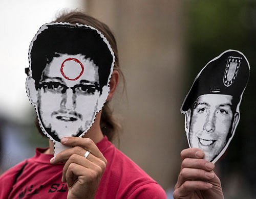 People hold portraits of former U.S. spy agency contractor Edward Snowden (L) and U.S. Army Private First Class Bradley Manning in front of their faces during a protest in front Brandenburg Gate in Berlin, July 4, 2013. Protesters demanded Germany grant Snowden asylum as they held up banners and chanted slogans in support of the former spy agency contractor. REUTERS