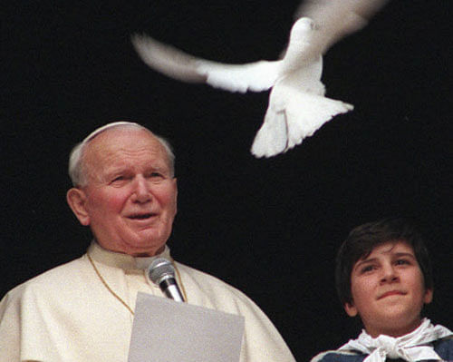 In this Jan. 28 1996 file photo, Pope John Paul II looks at a dove after he delivered the noon blessing from the window of his studio overlooking St. Peter's square at the Vatican. Pope Francis has cleared John Paul II for sainthood, approving a miracle attributed to his intercession. Francis also decided Friday, July 5, 2013, to canonize another beloved pope, John XXIII, even though there has been no second miracle attributed to his intercession. The Vatican said Francis approved a decision by cardinals and bishops. The ceremonies are expected before the end of the year. (AP Photo/Bruno Mosconi, File)