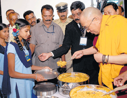 helping hand: The Tibetan spiritual leader, Dalai Lama, serves food to schoolchildren during his visit to the Iskcon temple in Bangalore on Friday. dh photo