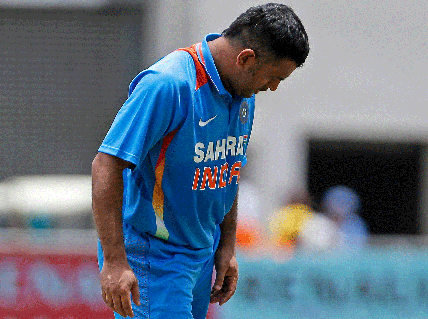 Mahendra Singh Dhoni removes the pad from his right leg after a light injury during the Tri-Nation Series cricket match against the West Indies in Kingston, Jamaica, Sunday, June 30, 2013. The Board of Control for Cricket in India (BCCI) announced on Monday that Dhoni has been ruled out of the ongoing Tri-Nation Series due to a hamstring injury and he will be replaced by Ambati Rayudu. (AP Photo)