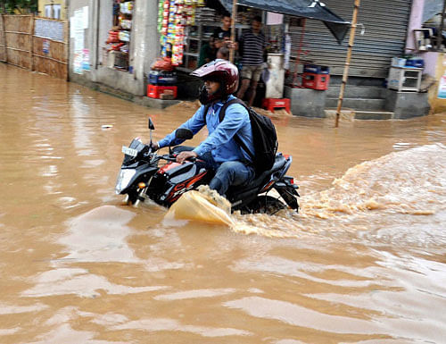 A motorcyclist wades through a waterlogged road after a heavy shower in Guwahati on Saturday. PTI Photo