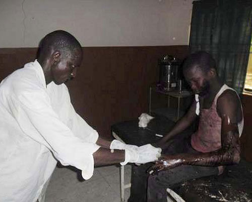 In this photo taken with a mobile phone a doctor attends to a student from Government Secondary School in Mamudo, at the Potiskum General Hospital, Nigeria, following an attack by gunmen on Saturday July 6, 2013. Islamic militants attacked a boarding school before dawn Saturday, dousing a dormitory in fuel and lighting it ablaze as students slept, survivors said. At least 30 people were killed in the deadliest attack yet on schools in Nigeria's embattled northeast. (AP Photo