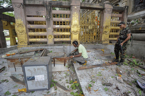 Security personnel inspect the site of an explosion inside the Mahabodhi temple complex at Bodh Gaya in the eastern Indian state of Bihar July 7, 2013. A series of explosions in and around Buddhism's holiest shrine in Bihar injured two persons early on Sunday, in what the government described as a 'terror' attack. The Mahabodhi Temple complex is located in Bodh Gaya, the place where the Buddha is believed to have attained enlightenment. REUTERS