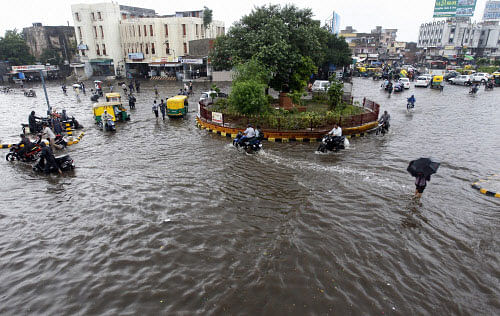 People cross flooded road after heavy rain in Ahmedabad on Thursday. PTI Photo