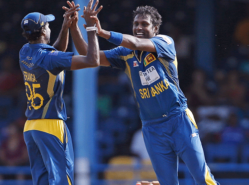 Sri Lanka captain Angelo Mathews, right, high fives teammate Shaminda Eranga after taking the wicket of West Indies' Darren Bravo, who was caught by Jeevan Mendis for 70 runs, during their Tri-Nation Series cricket match in Port-of-Spain, Trinidad, Monday, July 8, 2013. Sri Lanka won by 39 runs under the Duckworth-Lewis method. (AP Photo)