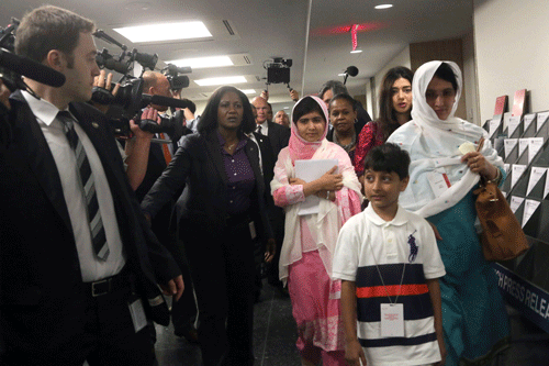 Malala Yousafzai, center, is escorted past members of the media, Friday, July 12, 2013 at United Nations headquarters. Malala Yousafzai, the Pakistani teenager shot by the Taliban for promoting education for girls, will celebrated her 16th birthday on Friday addressing the United Nations. (AP Photo