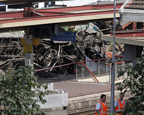 Railways workers are seen at the site where a train derailed at a station in Bretigny-sur-Orge, south of Paris, Saturday, July 13, 2013. An official on Saturday said a faulty rail joint may have caused a train derailment outside Paris that left six people dead and injured dozens. (AP Photo