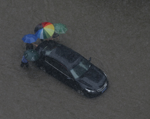 People help push a car on a flooded street during a rain storm in Wuhan, in central China's Hubei province.