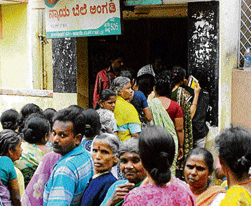People queue up to collect rice under Anna Bhagya scheme, at a fair price shop in Bangalore on Monday. KPN