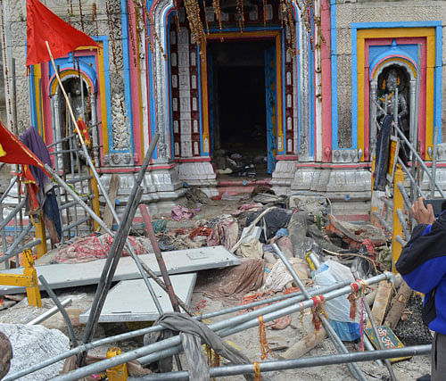 In this Thursday June 20, 2013, photo, a man takes pictures as bodies of pilgrims lying in from of the Kedarnath shrine, one of the holiest of Hindu temples dedicated to Lord Shiva at Kedarnath. Huge cracks have developed in some places of the Kedarnath shrine according to preliminary assessment of the Archaeological Survey of India (ASI). AP Photo